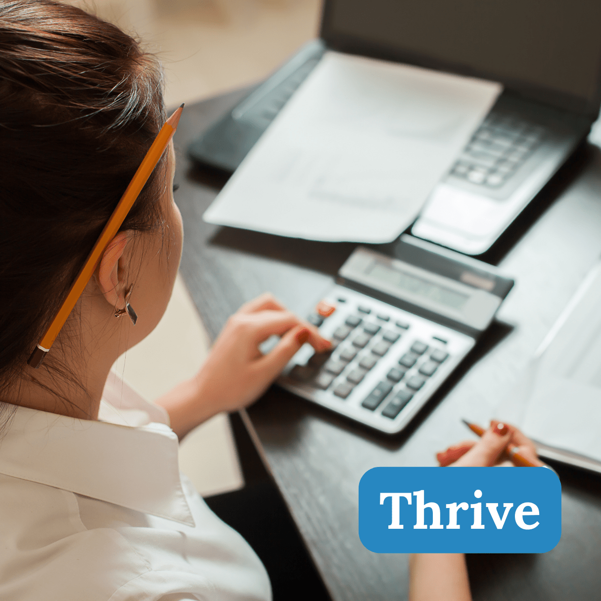 An image of a woman on a calculator with paperwork on a desk. The words titled "Thrive" are on top.